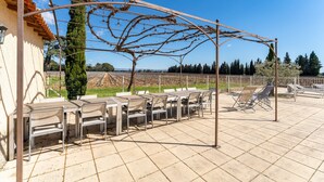 An outdoor patio with tables and chairs, a pergola with vines, and a view of the countryside. - Château Mazane – Mas in the Heart of Vineyards, Pool and Mountain View (Sarrians)