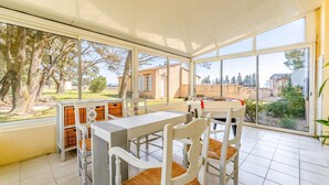 A covered patio with a table and chairs, large windows, and a view of the outdoors. - Château Mazane – Mas in the Heart of Vineyards, Pool and Mountain View (Sarrians)
