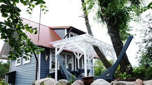 A house with a porch, a wooden deck, and a stone wall. - Comfortable Holiday Homes With a Beautiful Garden (Parchowo)