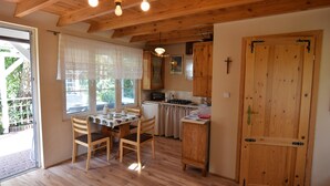 A wooden interior with a dining table, chairs, a kitchen area, and a large wooden door. - Comfortable Holiday Homes With a Beautiful Garden (Parchowo)