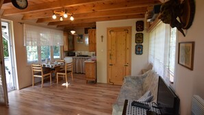 A cozy living room with a wooden floor, a dining area with a table and chairs, a sofa with a laptop, and a kitchen in the background. - Comfortable Holiday Homes With a Beautiful Garden (Parchowo)