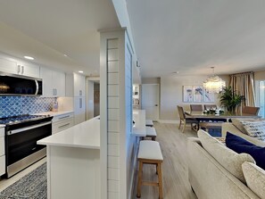 Cozinha moderna com armários brancos, painel de azulejos azuis e uma ilha central.