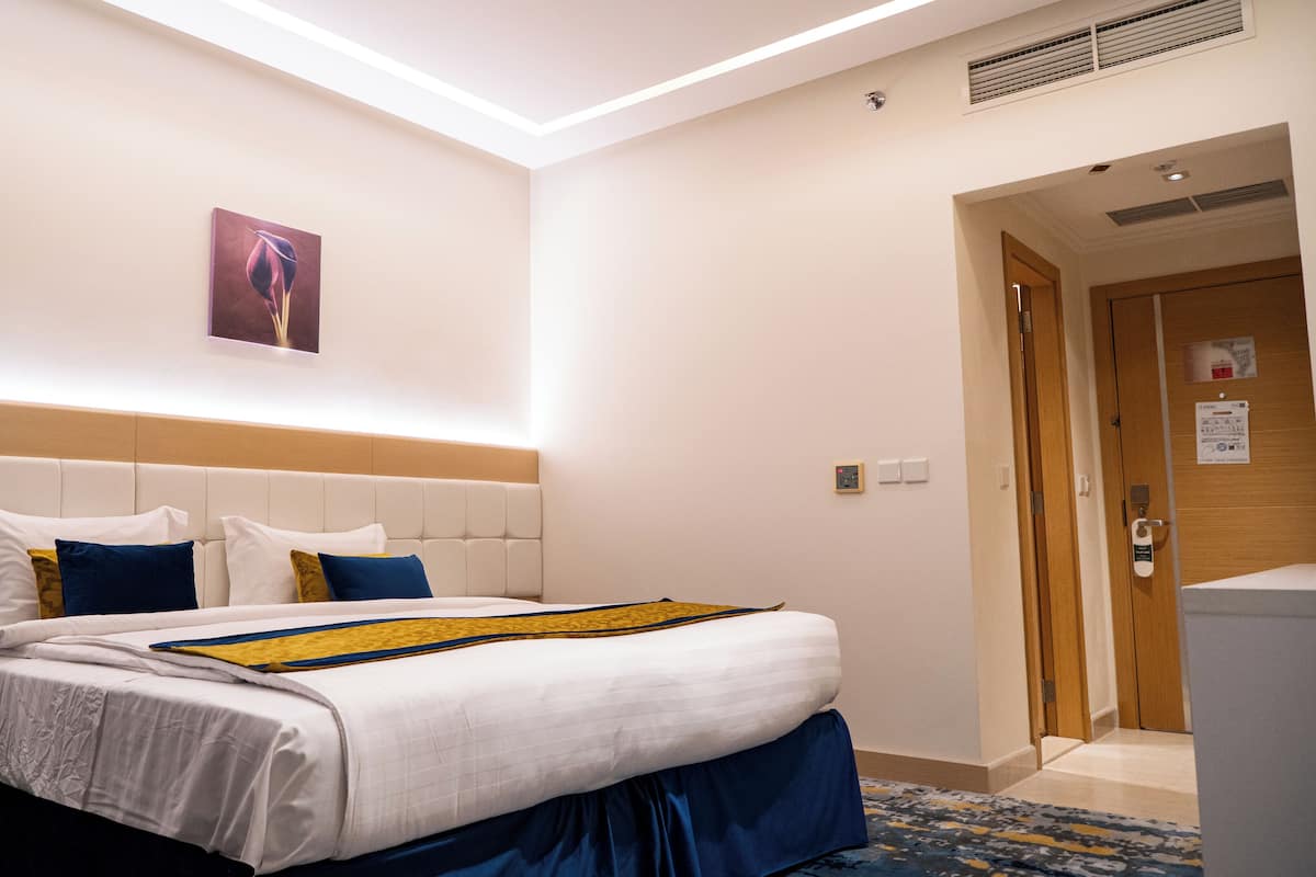 Ein Hotelzimmer mit einem Bett, einem Nachttisch, einem Telefon und zwei an der Wand hängenden Bildern.