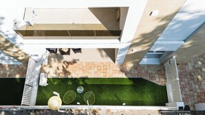Un toit-terrasse doté d’une zone recouverte de gazon synthétique, d’une structure blanche et d’un mur en briques.