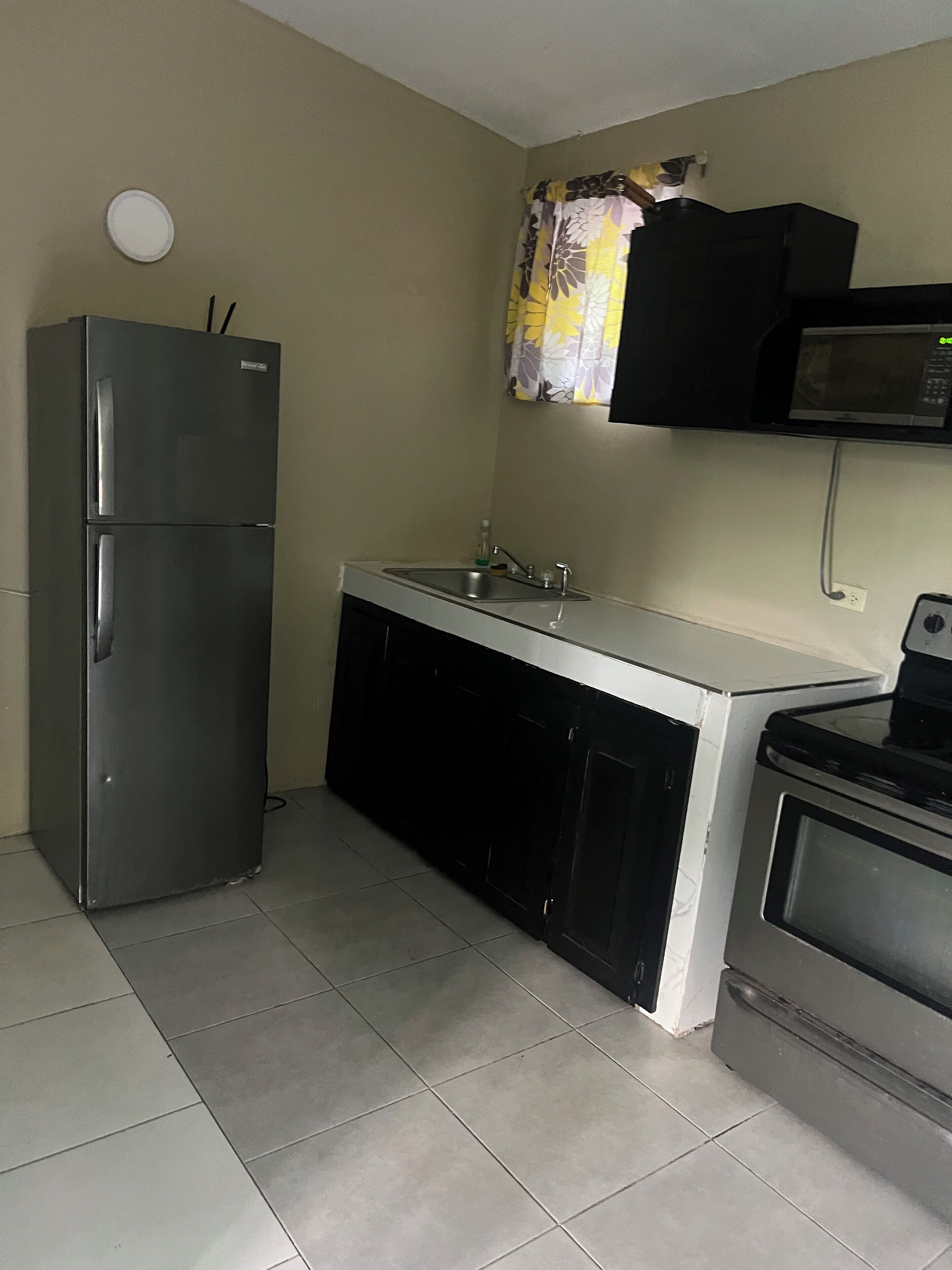 A compact kitchen with a refrigerator, a microwave, and an oven.