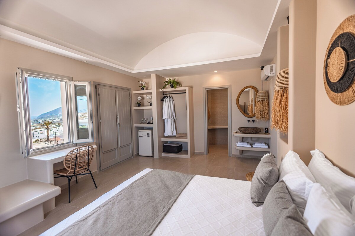 A bedroom with a bed, a desk, a chair, a wardrobe, and a view of the outside.