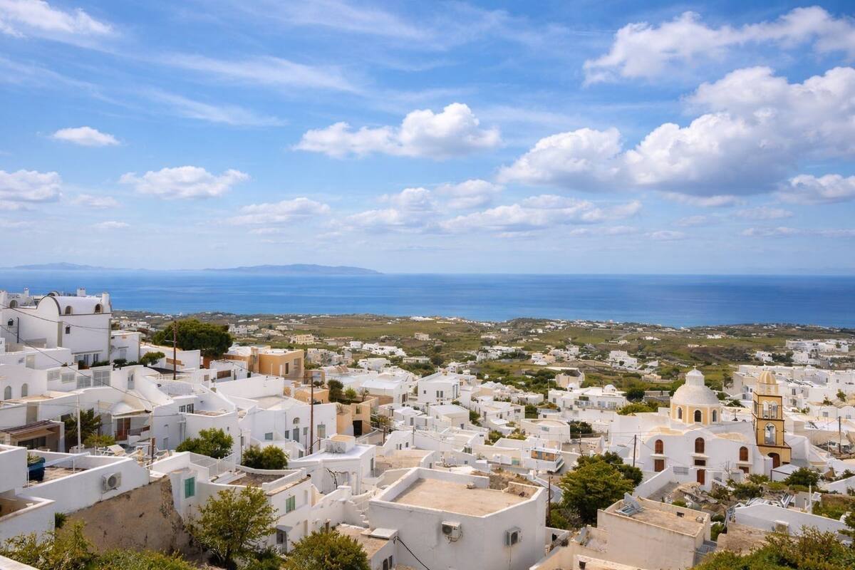 A coastal town with white buildings, a clear sky, and the sea in the background.
