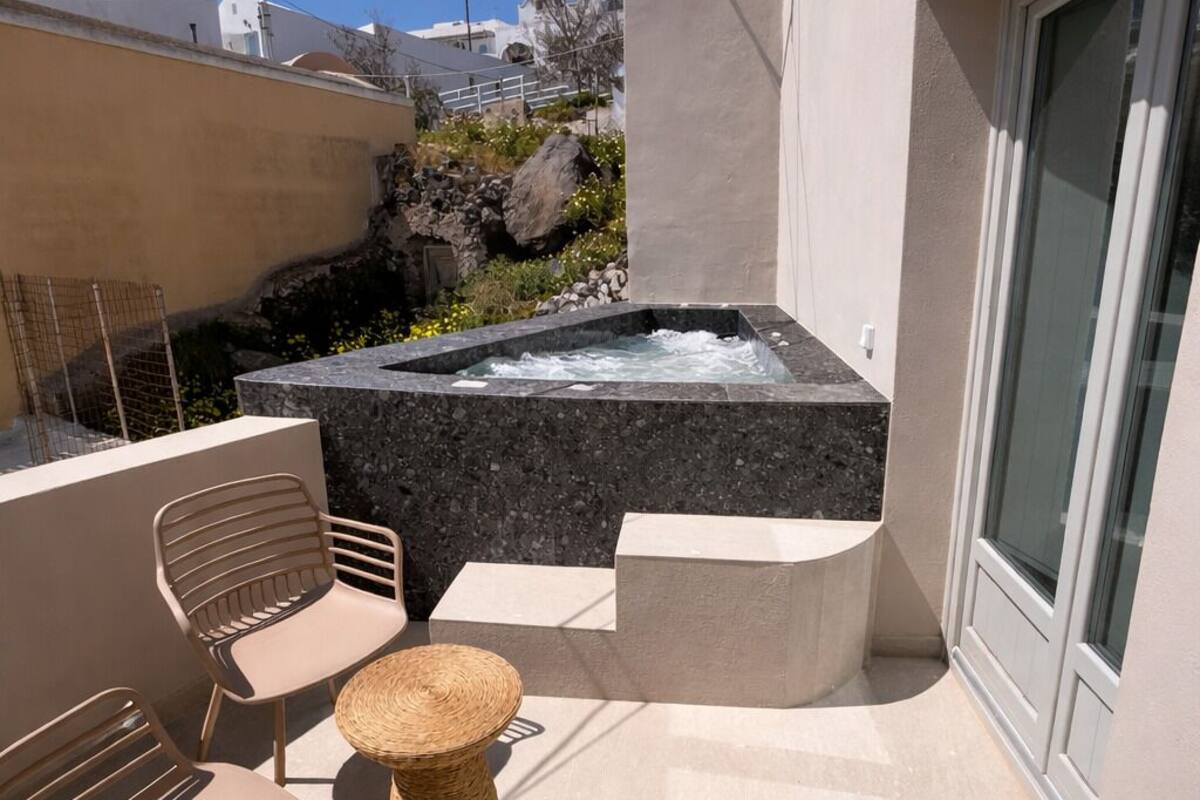 A modern outdoor patio with a hot tub, seating area, and a stone wall.