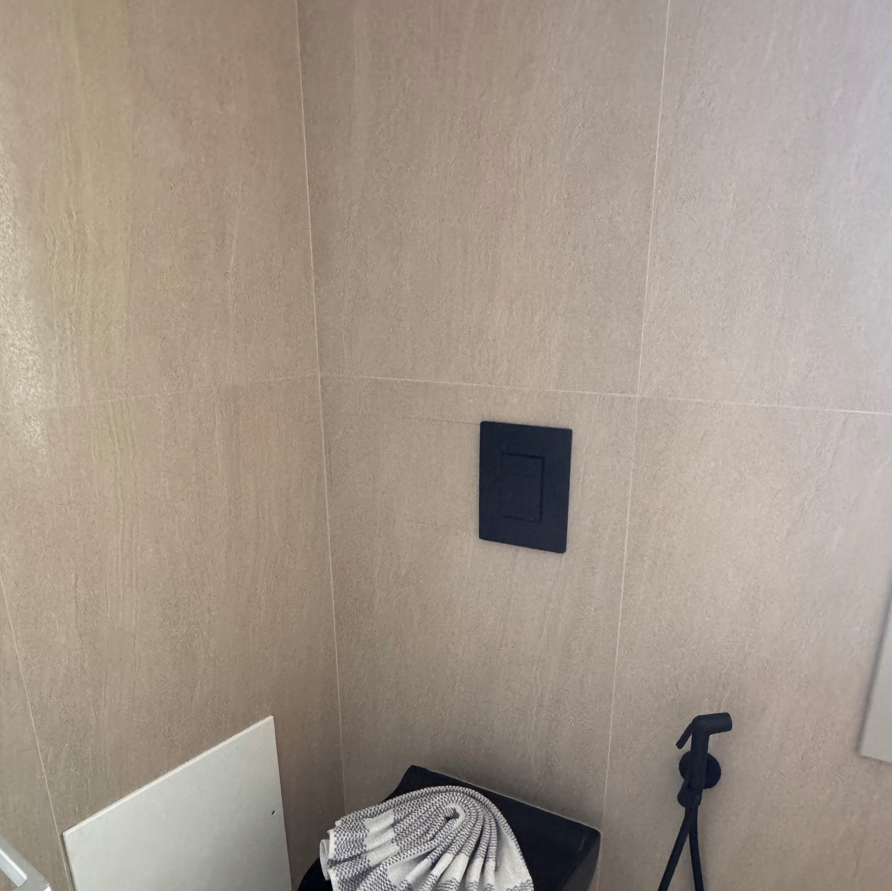 A bathroom with beige tiles, a towel rack, and a showerhead.