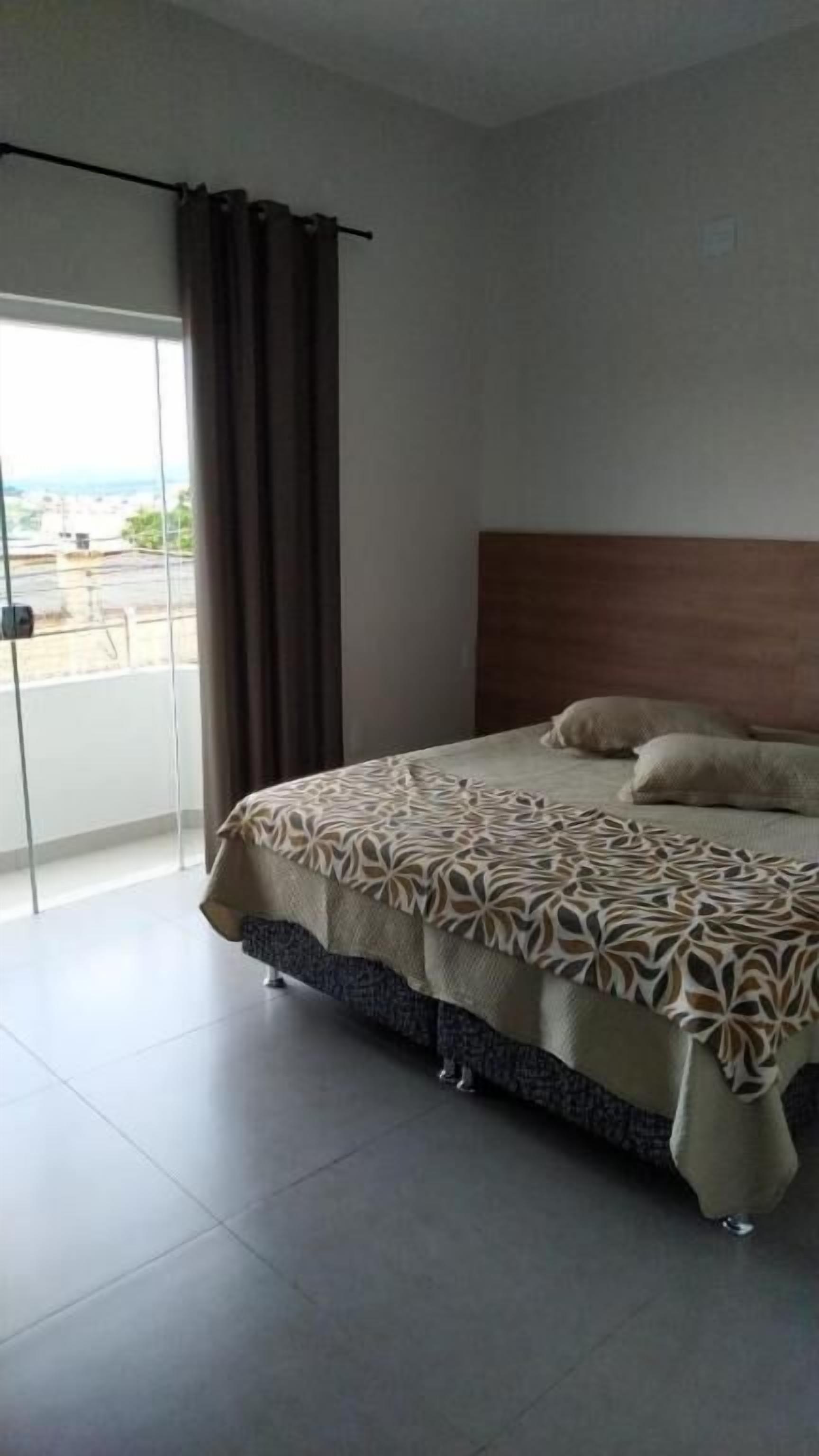 A bedroom with a bed, a view through a glass door, and a curtain.