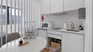 Eine moderne Küche mit weißen Schränken, einer Mikrowelle, einem Spülbecken und einem Essbereich mit Tisch und Stühlen.