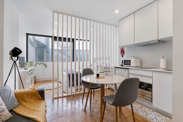 Une cuisine moderne avec des meubles blancs, un four à micro-ondes et un coin repas comprenant une table ronde et des chaises.
