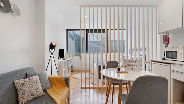Ein moderner Wohnraum mit einer Couch, einem Esstisch und einer Küchenzeile.