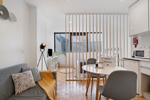 Un espacio habitable moderno con sofá, mesa de comedor y área de cocina.