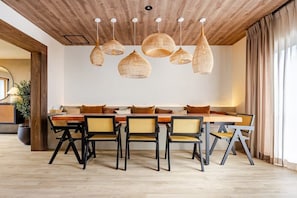 A dining area with a long wooden table, six chairs, and woven pendant lights.