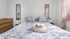 Ein Schlafzimmer mit einem Bett, zwei Nachttischen, einer Kommode und einem Spiegel an der Wand.