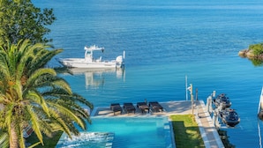Ein Boot liegt an einem Pool mit Liegestühlen und einer Palme.