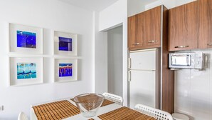 A modern kitchen with wooden cabinets, a microwave, and a refrigerator. There are framed pictures on the wall and a table with placemats. - Sunny Apartment with Terrace in El Médano (El Medano)