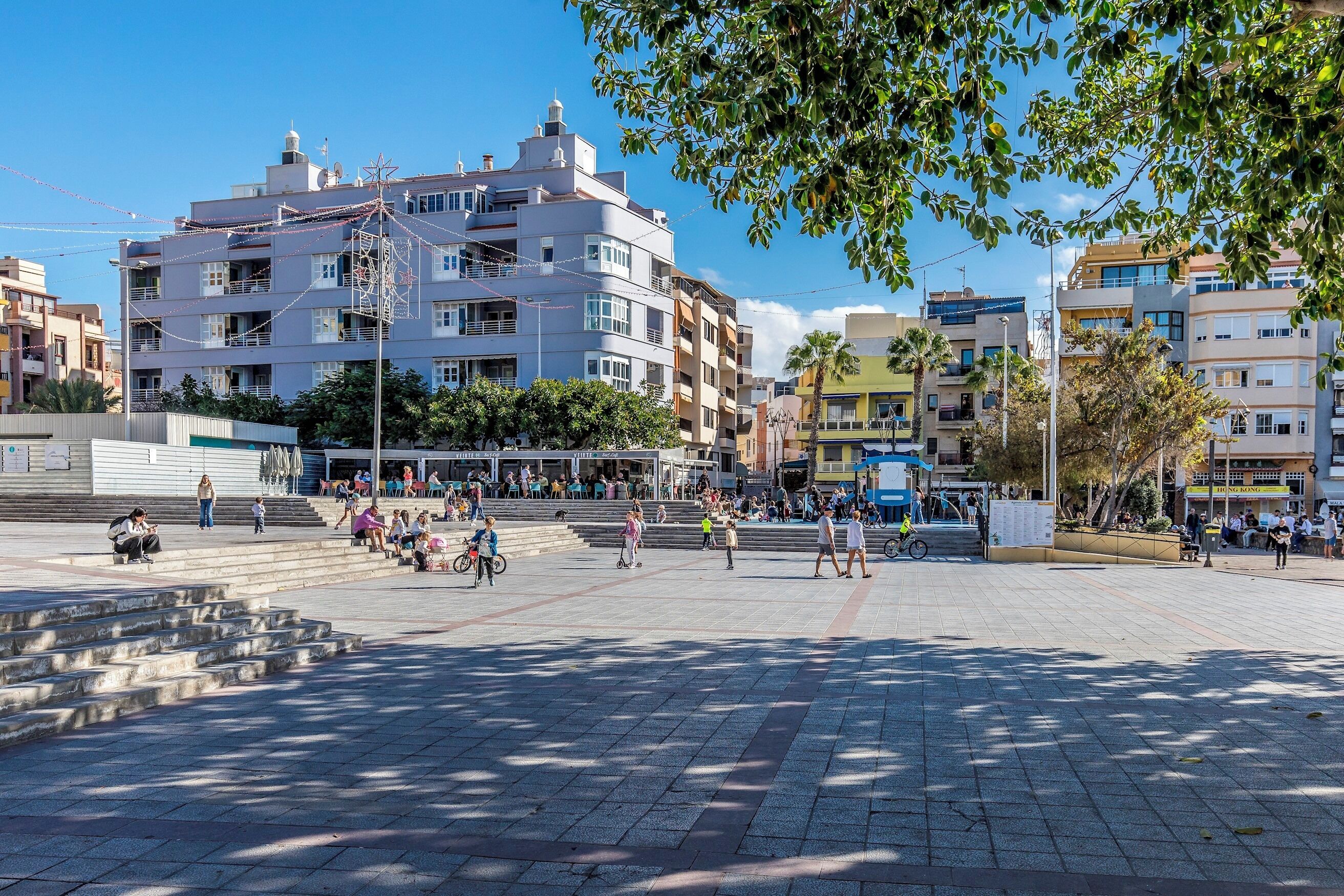 A public square with steps leading up to a building with multiple floors and balconies.