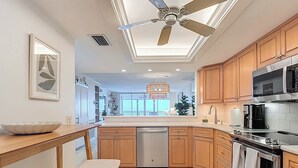Una cucina moderna con mobili in legno, forno in acciaio inossidabile, microonde e ventilatore a soffitto.