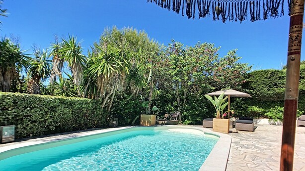 Une piscine à l’eau d’un bleu cristallin, entourée d’une végétation luxuriante et agrémentée d’une terrasse en pierre.