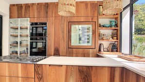 Une cuisine moderne avec des meubles en bois, des appareils électroménagers intégrés et une grande fenêtre offrant une vue sur l’extérieur.