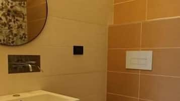 A bathroom with a wooden floor, a white sink, a toilet, and a bidet.