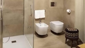 A modern bathroom with a glass shower enclosure, a bidet, a toilet, and a small stool. - HOTEL ARIMANNIA (Caramanico Terme)