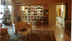 A living room with a Christmas tree, a sofa, a coffee table, and a wall of wine bottles. - HOTEL ARIMANNIA (Caramanico Terme)