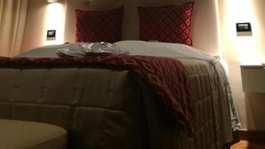 A bedroom with a wooden ceiling, a bed with a red and white bedspread, and two wall-mounted lights. - HOTEL ARIMANNIA (Caramanico Terme)