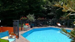 A swimming pool with lounge chairs and a wooden deck. - HOTEL ARIMANNIA (Caramanico Terme)