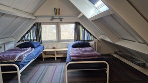 Ein Schlafsaalzimmer mit zwei Betten, einem kleinen Tisch und einem Fenster mit Vorhängen.