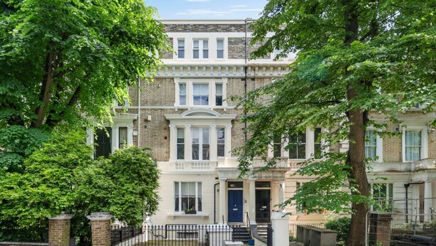 A row of terraced houses with a central entrance, brick walls, and a small front garden. - Argyl | Cambridge Gardens: Apt. B (Greater London)