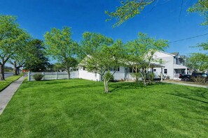 A residential property with a well-maintained lawn, a white house with a porch, and a driveway. - Pet-Friendly Cozy Cape Escape Near Beach (Lower Township)