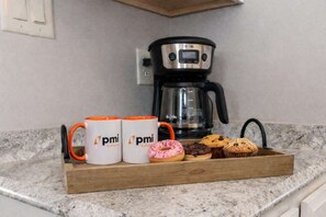 A kitchen counter with a coffee maker, two mugs, and a tray of baked goods. - Pet-Friendly Cozy Cape Escape Near Beach (Lower Township)