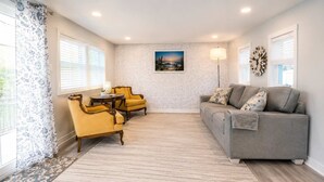 A living room with a sofa, two armchairs, a coffee table, a floor lamp, and a painting on the wall. - Pet-Friendly Cozy Cape Escape Near Beach (Lower Township)