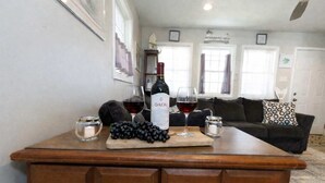 A wooden dining table with a bottle of wine, glasses, and grapes. - Pet-Friendly Cozy Cape Escape Near Beach (Lower Township)