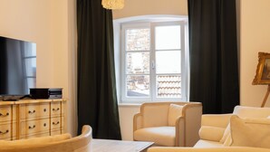 A living room with a television, a wooden cabinet, a window with curtains, and a white sofa. - ღLiboria | Villa Münter (Murnau am Staffelsee)