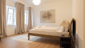 A bedroom with a wooden bed, a bedside lamp, a large window with curtains, and a wall-mounted artwork. - ღLiboria | Villa Münter (Murnau am Staffelsee)