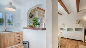 Eine moderne Küche mit Holzschränken, einer Marmorarbeitsplatte, einer Hängelampe und einem Mülleimer.