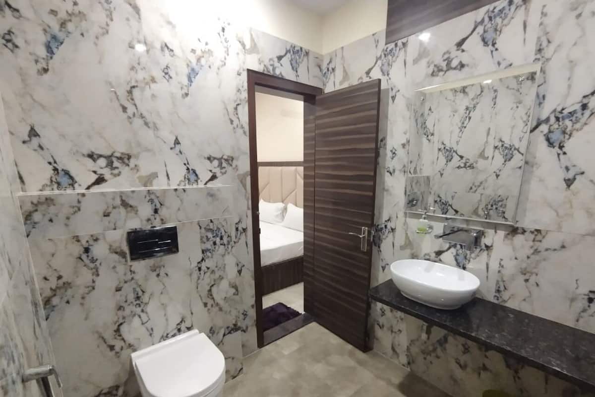 A bathroom with marble walls, a white toilet, a sink, and a mirror.