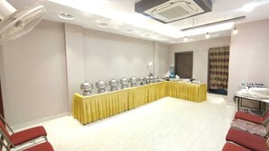 A conference room with a long table covered in yellow, surrounded by red chairs, and equipped with ceiling lights and an air conditioning unit. - hotel nandini palace (Varanasi)