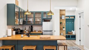 A modern kitchen with a central island, bar stools, and a teal cabinetry. - Fully Updated 2 Bedroom Apartment - In Downtown and Steps from Green Lake (Green Lake)