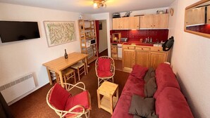 Un espace de vie compact comprenant un coin cuisine, un coin repas et un espace détente avec un canapé et des fauteuils.