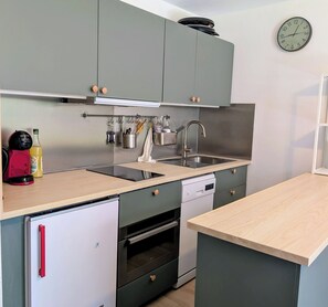 Cocina compacta con fregadero, estufa y refrigerador pequeño.