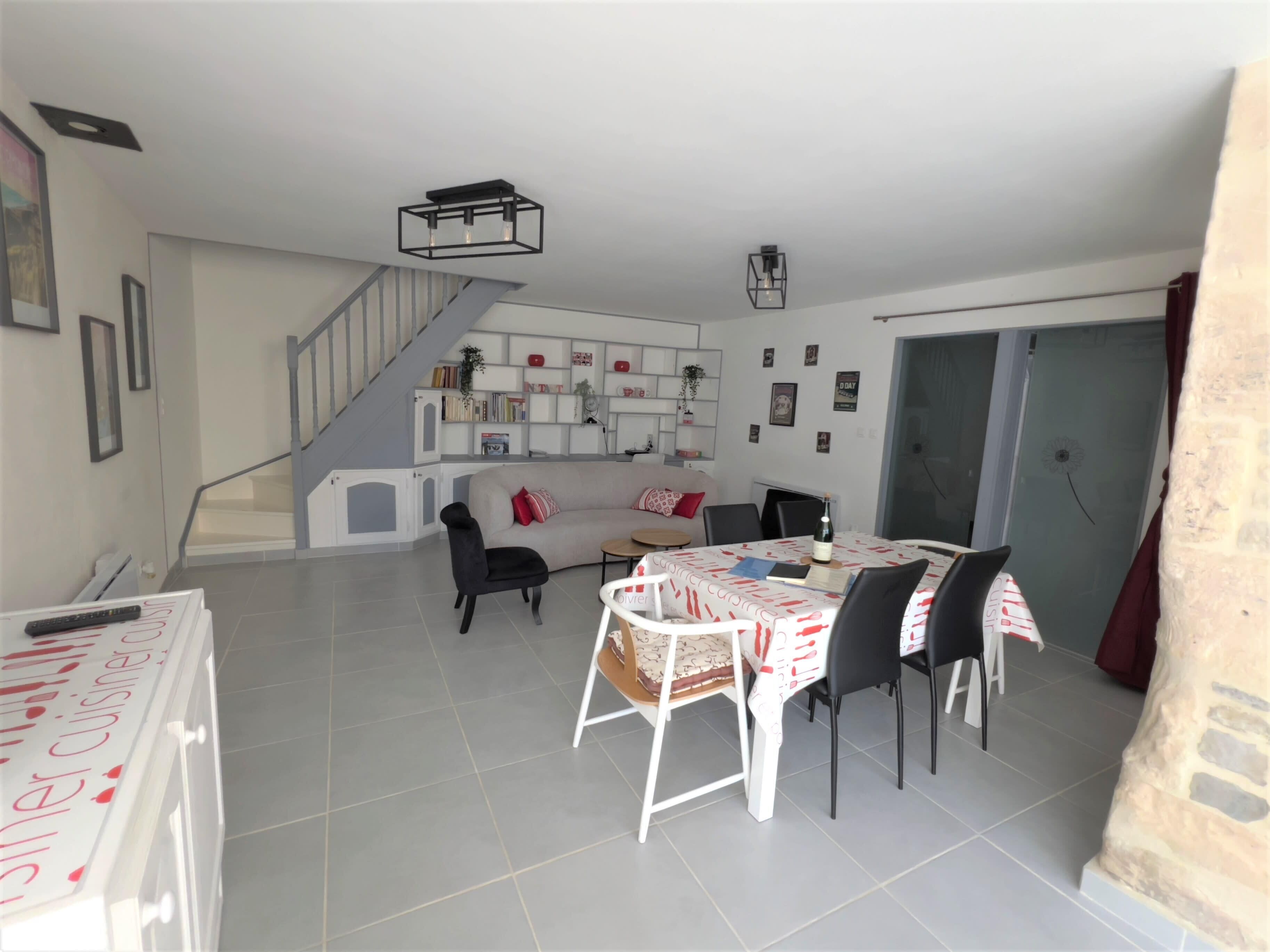 A modern living room with a staircase, a dining area, and a kitchen.