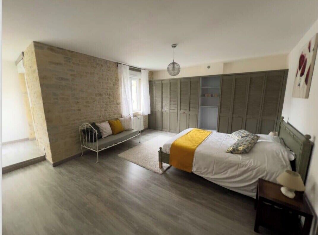 A bedroom with a bed, a bench, a wardrobe, and a hanging light fixture.