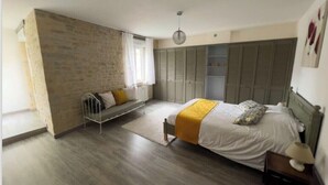 Un dormitorio con cama, un banco, un armario y una lámpara colgante.