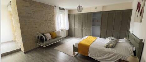 A bedroom with a bed, a bench, a wardrobe, and a hanging light fixture.