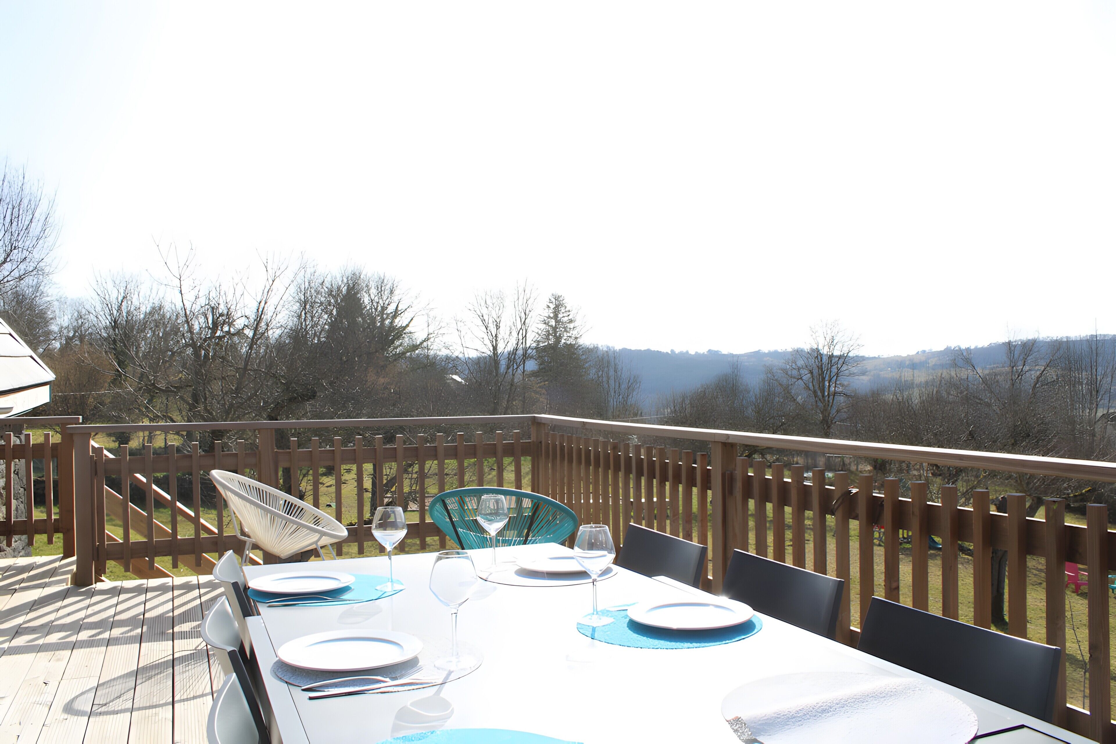 Un espace de restauration en plein air avec une table dressée pour quatre personnes, des chaises et une vue sur le paysage environnant.